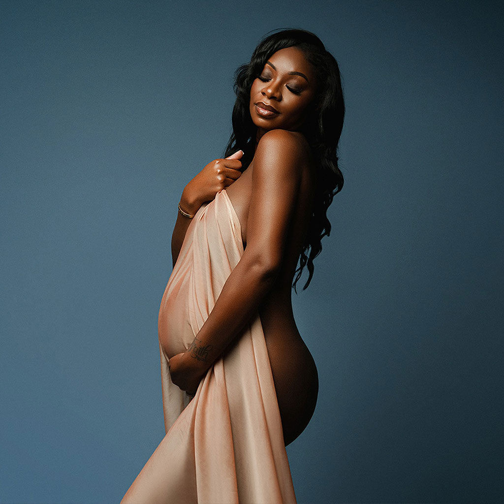 Maternity photography backdrops - a pregnant woman holding a beige fabric against a dark blue background - Seascape backdrop