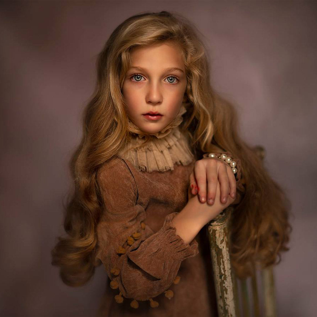 Children's photography backdrops - Young girl in a brown dress with a textured collar against a soft purple background