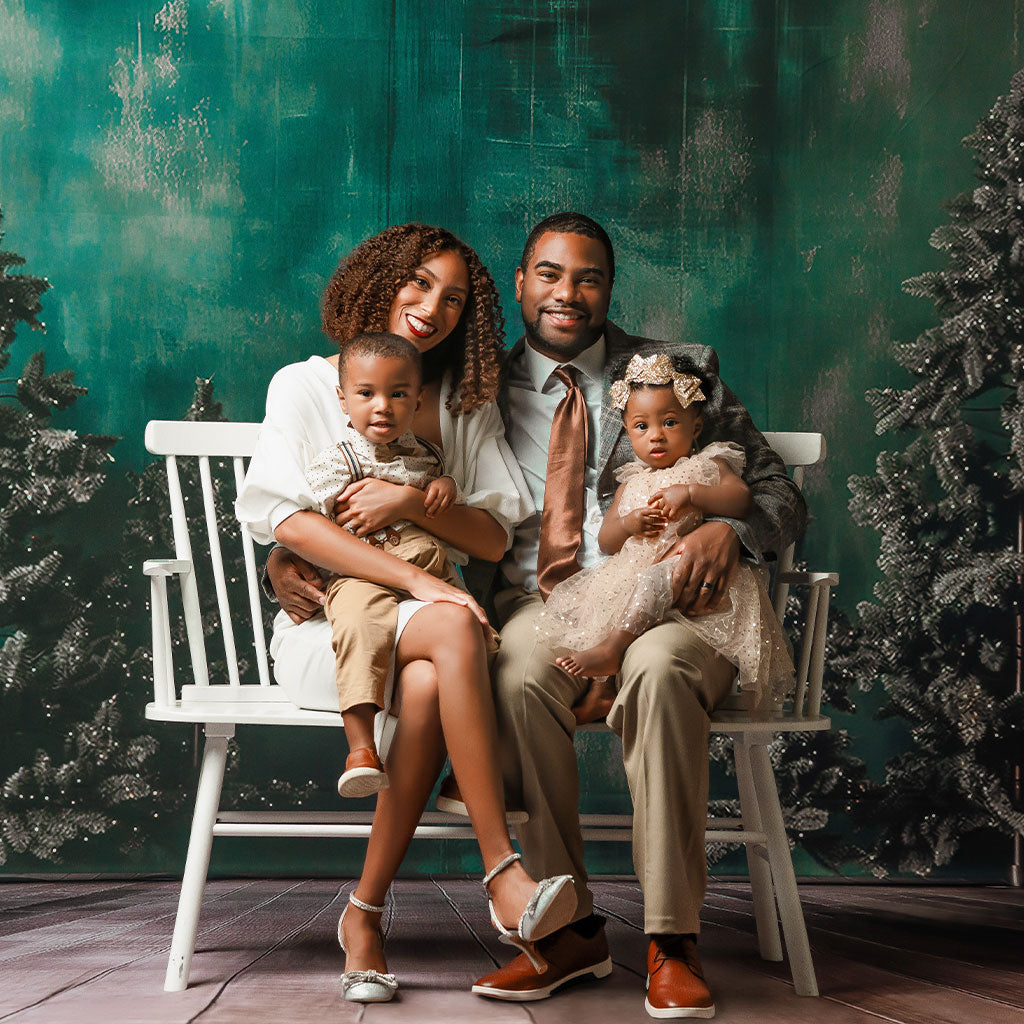Christmas photography backdrops - A family of four sitting on a white bench with a festive holiday background