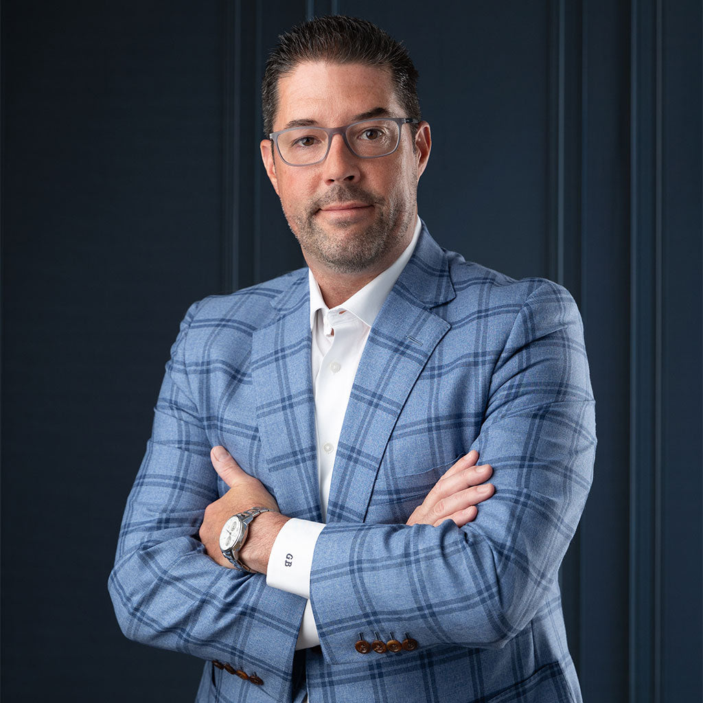 Headshot photography backdrops - A professional businessman in a blue checkered suit with arms crossed against a dark background