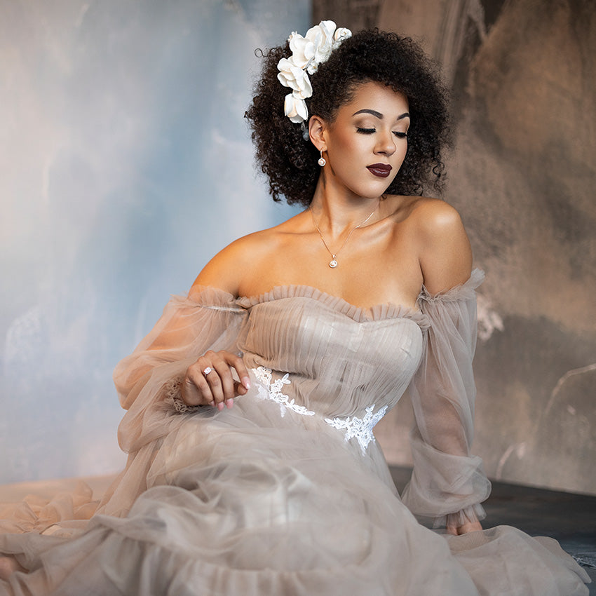 Room photography backdrop for portraits. Woman in a light-colored dress with sheer sleeves against a soft, blurred background